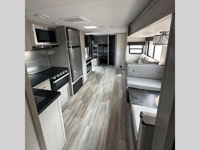 Prime Time RV Tracer 28BHS interior with bunks, a kitchen, a dinette, a sofa, and a slide out