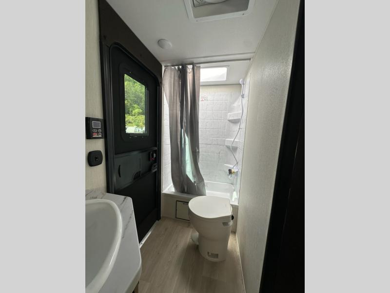 Forest River RV Cherokee Grey Wolf 26DBH bathroom with a shower, tub, foot-flushing toilet and a sink with a door to the exterior.